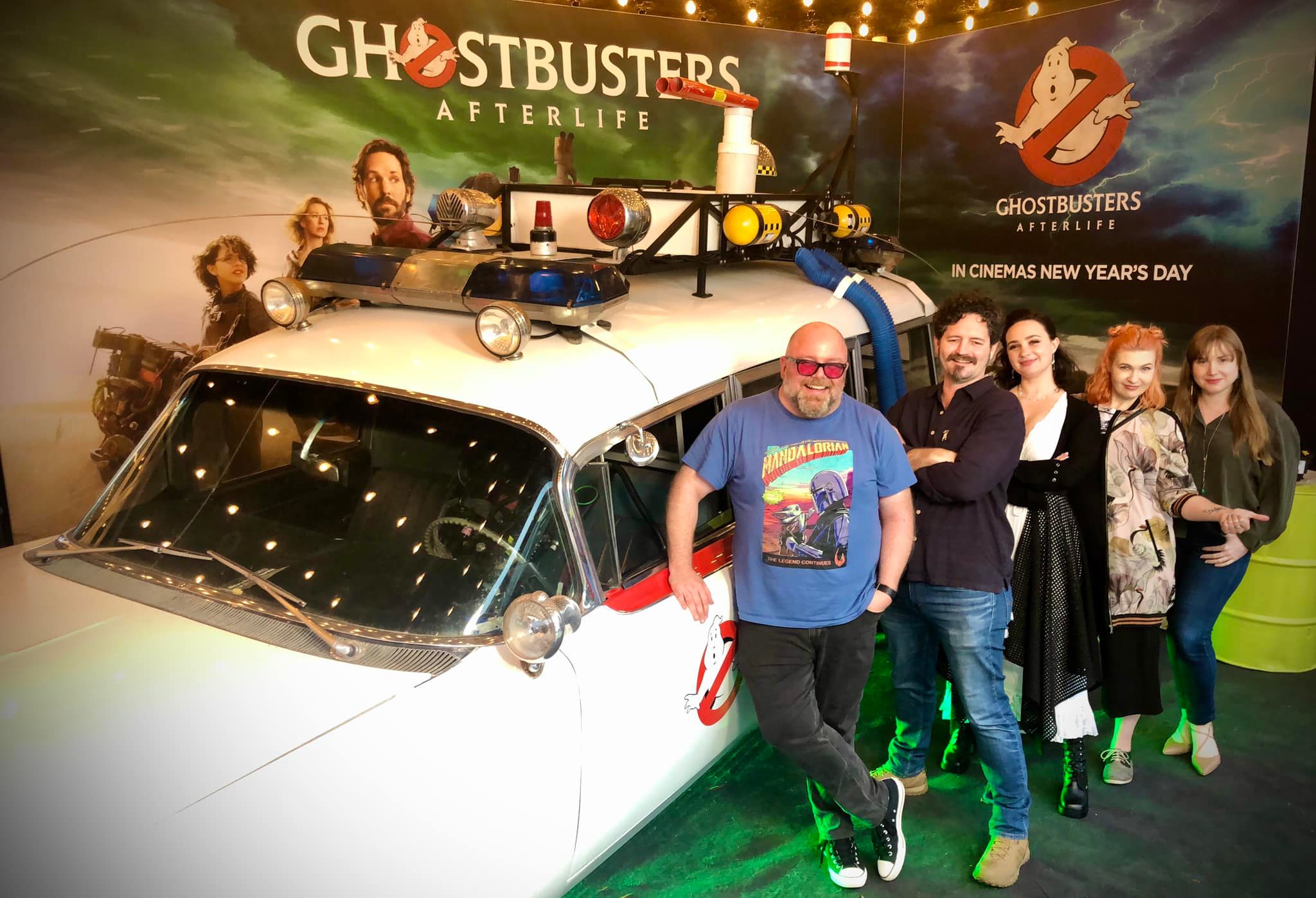 the team of Quinny, Dion, Bec, Peta and Jill pose in front of an Ecto 1 replica vehicle