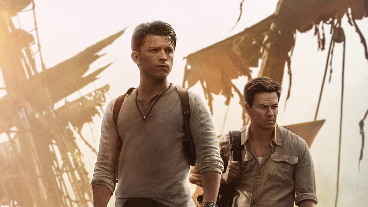 Tom Holland and Mark Wahlberg stand in front of decaying Galleon sails.