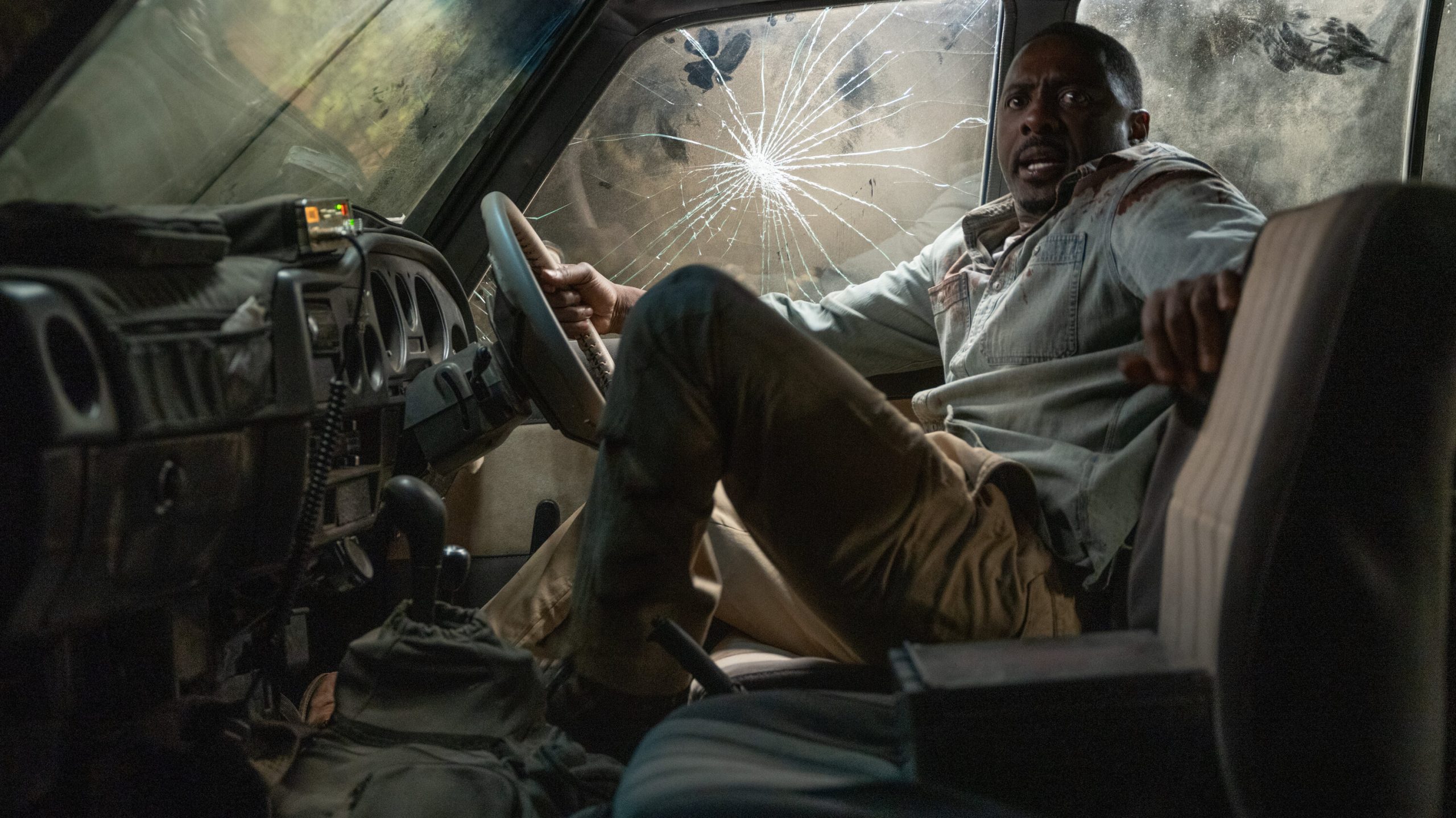 Idris elba in a semi detroyed car terrified of somrthign off screen